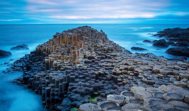 Causeway Coastal Route Северная Ирландия Тысячи шестиугольных базальтовых колонн считаются мостовой троллей прошедших здесь от гнева Одина и других богов На самом же деле эти причудливые скальные образования результат извержения вулкана